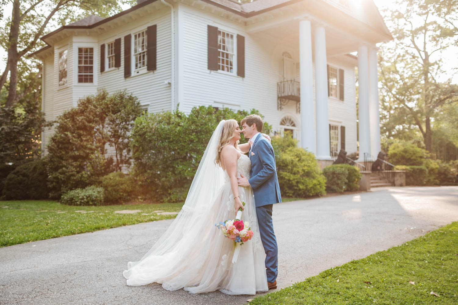 A bride and groom, radiating joy, share a moment in front of the elegant Duncan Estate.