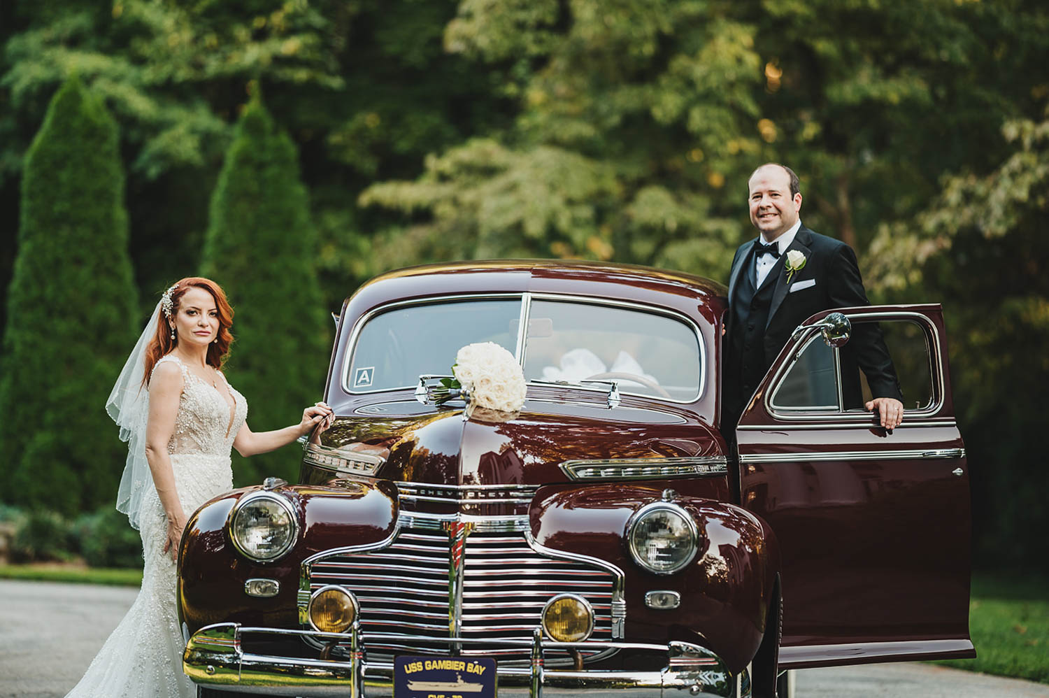 A wedding couple getting into an old car to drive away