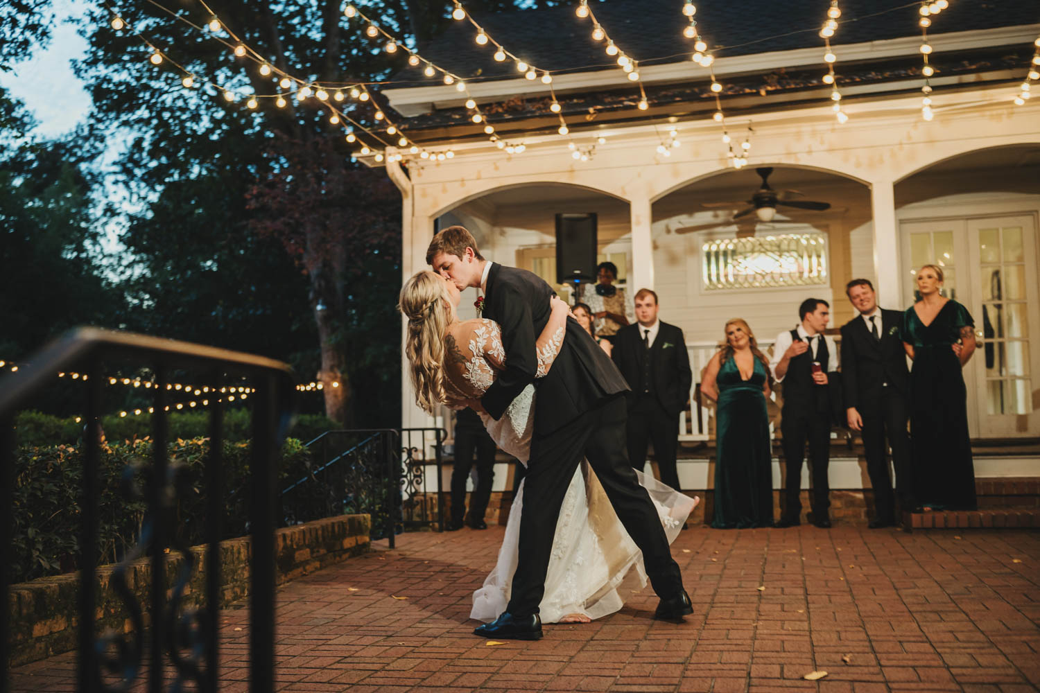 Kissing couple with friends looking on under lights