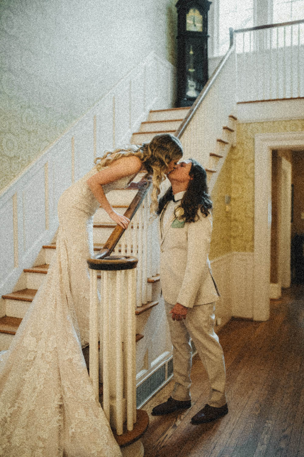 Woman leaning over stairs railing to kiss her husband