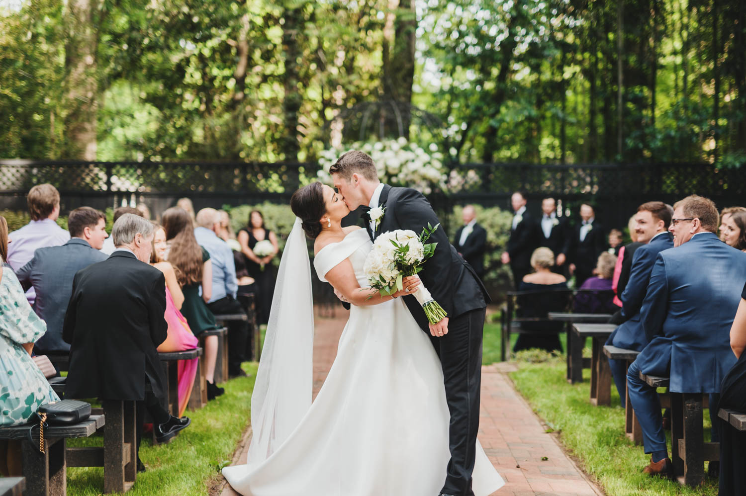 Husband and wife leaning over to kiss down the wedding aisle