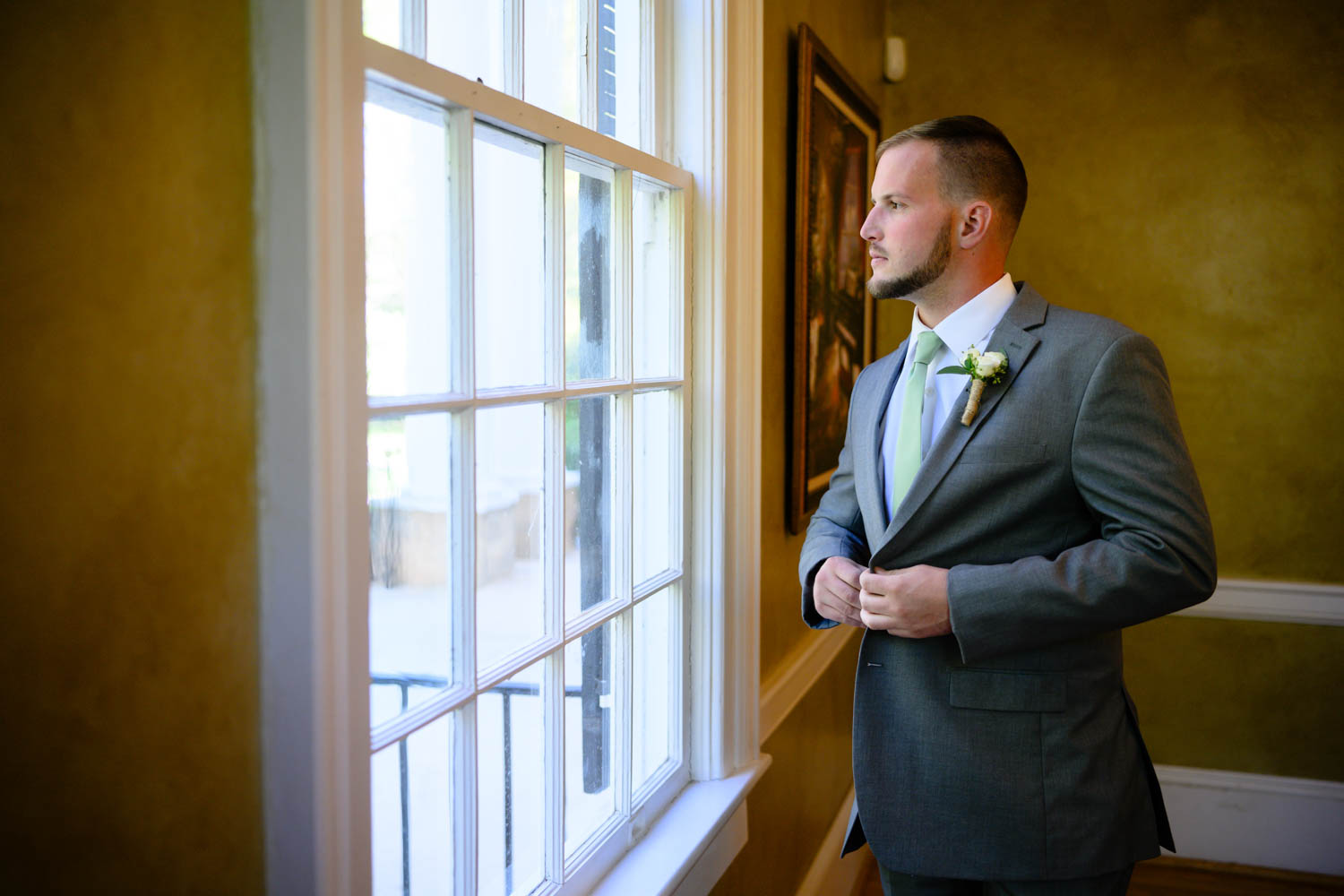 Groom staring out a window before the wedding ceremony