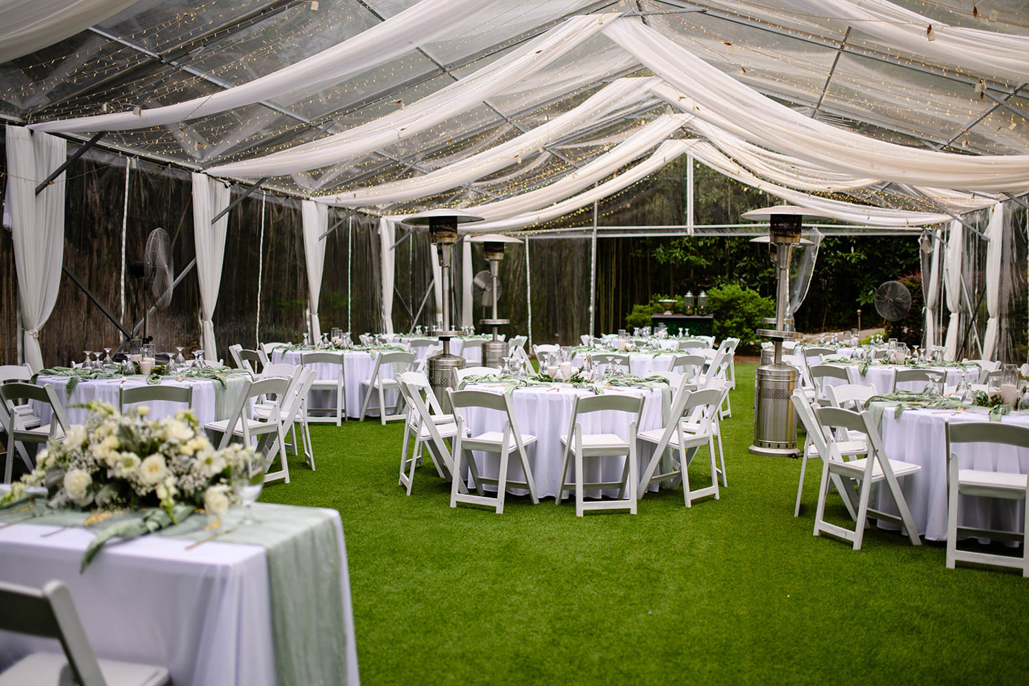 White table and chairs under a white tent for a wedding reception