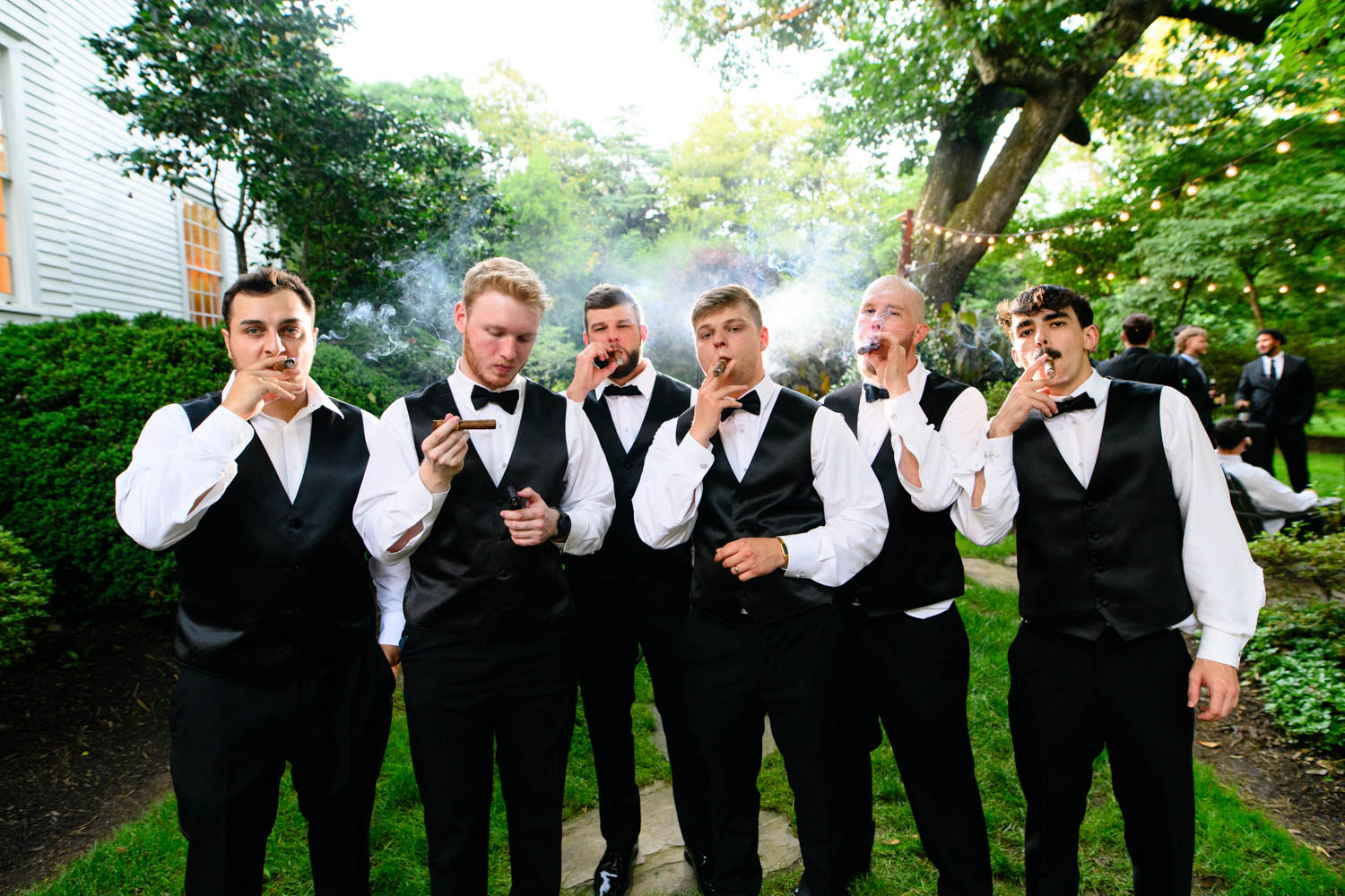 Groom with groomsmen posing with jackets slung over shoulder