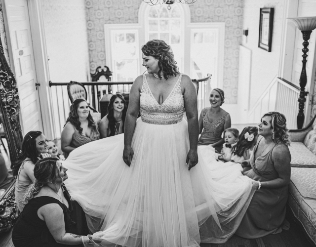 Bridesmaids standing around bride fixing her dress